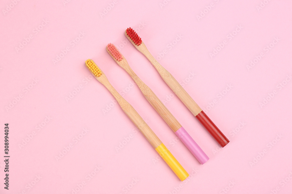 Toothbrushes made of bamboo on pink background, flat lay Toothbrushes made of bamboo on pink background, flat lay