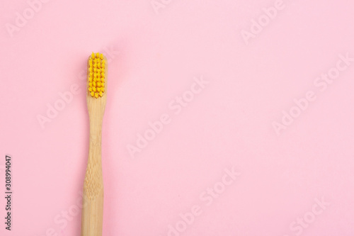 Toothbrush made of bamboo on pink background  top view. Space for text