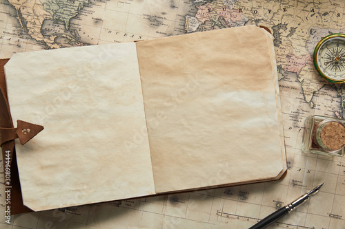 top view of vintage blank notebook with fountain pen near compass on map background