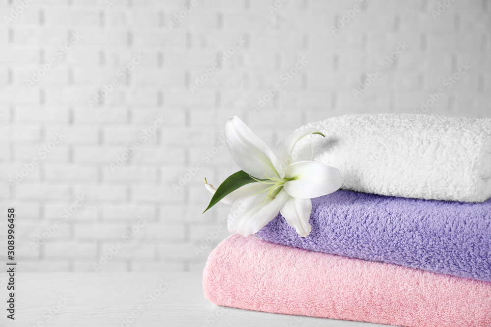 Stack of clean bath towels and beautiful flower on white wooden table. Space for text Stack of clean bath towels and beautiful flower on white wooden table. Space for text