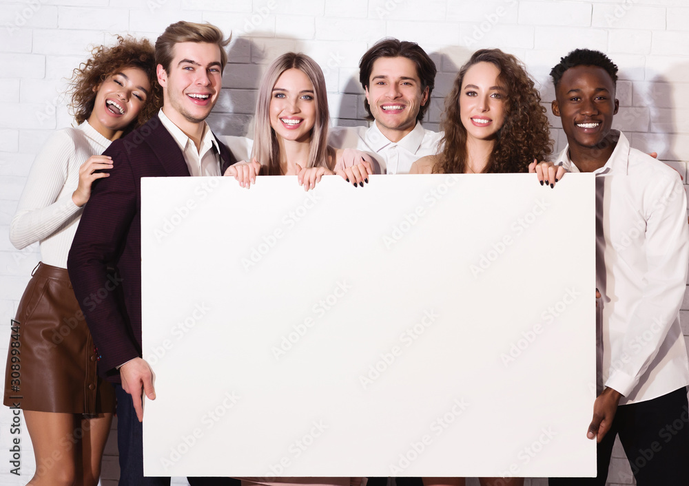 Diverse Friends Holding Blank Board Standing Over White Wall Indoor Diverse Friends Holding Blank Board Standing Over White Wall Indoor