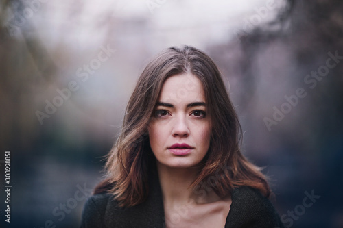 Bilde på lerret Attractive charming young woman in a dark coat walking in the autumn park