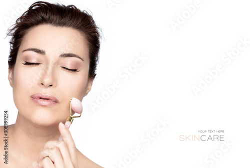 Beautiful woman with healthy fresh clean skin using a face roller massager