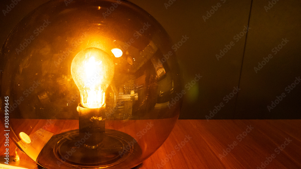 A light bulb in a glass sphere. Wood table.