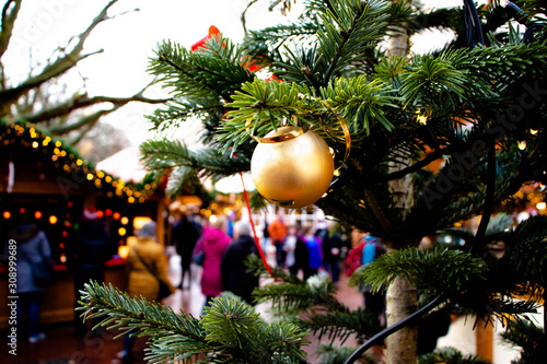 Golden Christmas ball on a fir tree at the crowded Christmas market © Zarahzeta®
