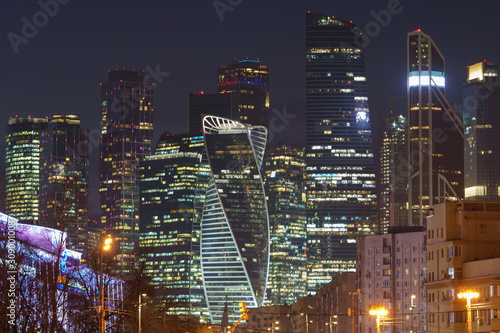 Moscow cityscape in winter night. Modern business skyscrapers over the residential houses. City is full of neon and street lights. High resolution photography.