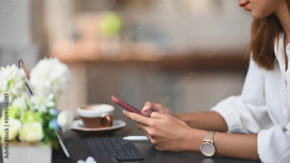 Cropped shot woman using her smartphone on table. Cropped shot woman using her smartphone on table.