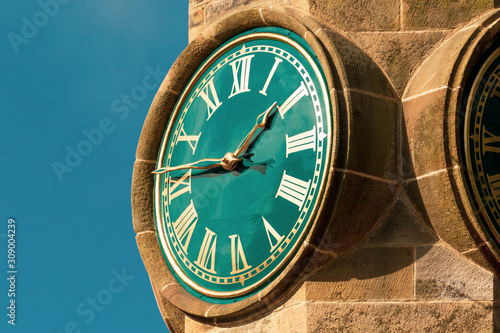 Foto Tower clock with roman numerals against blue sky