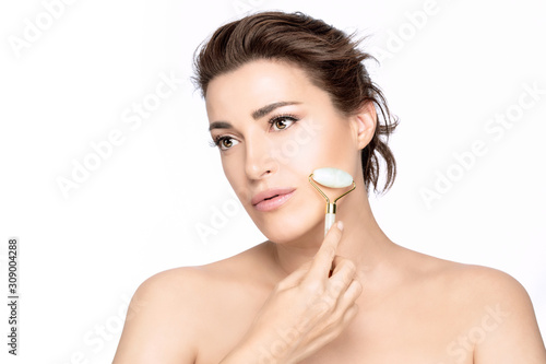 Fotografie Beautiful woman with healthy fresh clean skin using a roller face massager