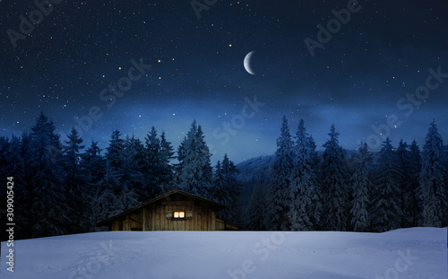 Beleuchtete Holzhütte in einer Winternacht © by-studio