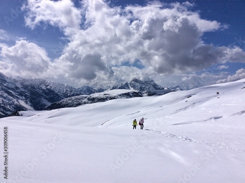 Tourists walk away in the snowy mountains during the day in fine weather. Mountain tourism concept in the Dolomites.