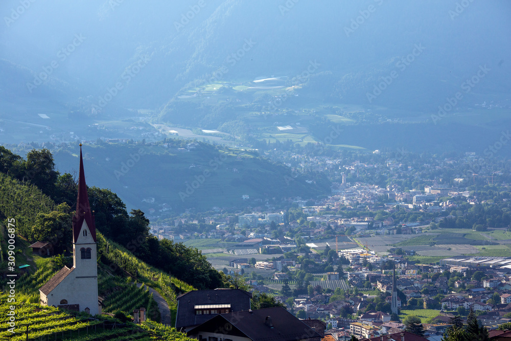 Fototapeta premium A view of the city of Meran and surrounding area from up in the hillscreasing in South Tyrol