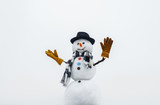Christmas and winter fashion. Happy snowman waving in hand. Happy holiday celebration. Christmas snowman in hat, scarf, gloves. Merry christmas and happy new year. Happy snowman in winter. Wintertime.