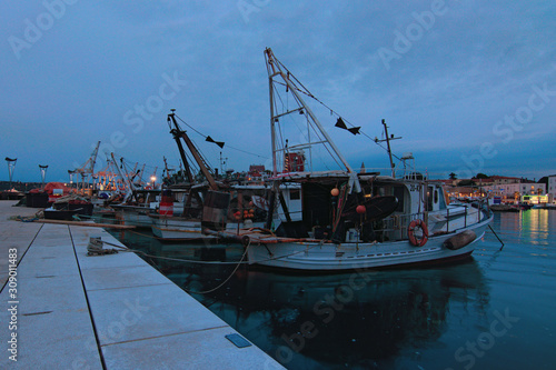 Koper, Slovenia-September 27, 2019: Scenic evening view of harbor in Koper. Vintage fishing boats moored in harbor. Beautiful autumn evening. Romantic and peaceful scene