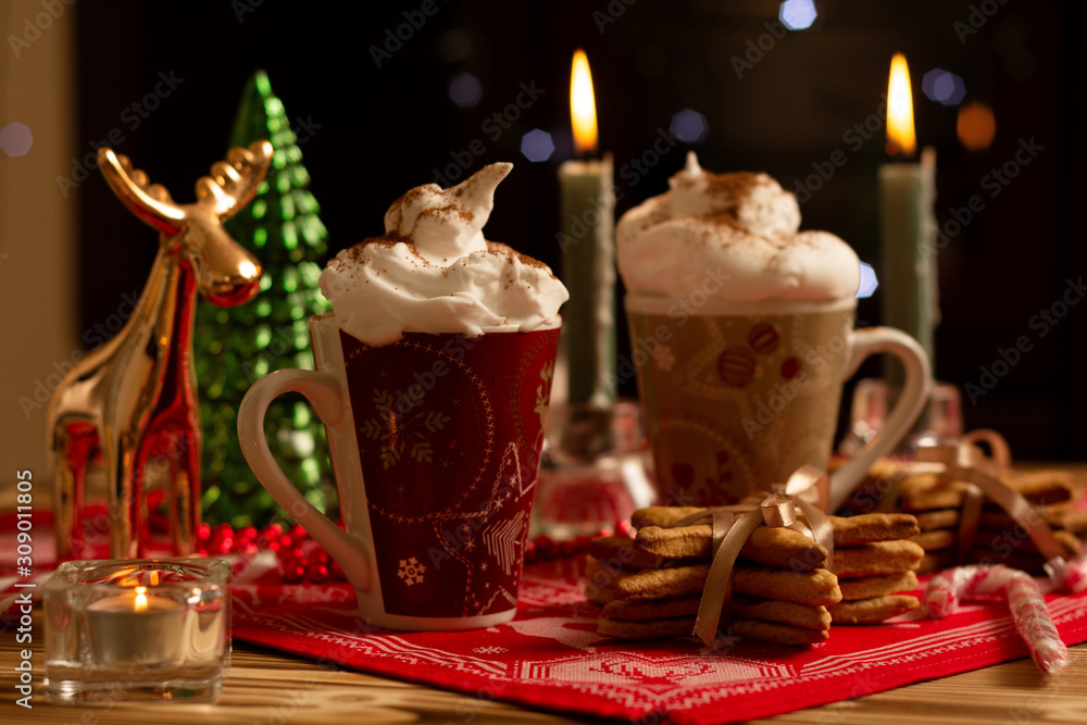 Horizontal view of hot spicy cinnamon creamy drinks in Christmas mug with burning candles and decorations