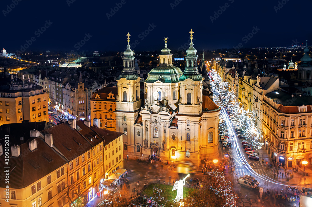 Aerial view of Old Town square with illuminated St. Nicholas' Church, a hussite place of worship built in the 12 century at night in Prague, Czechia