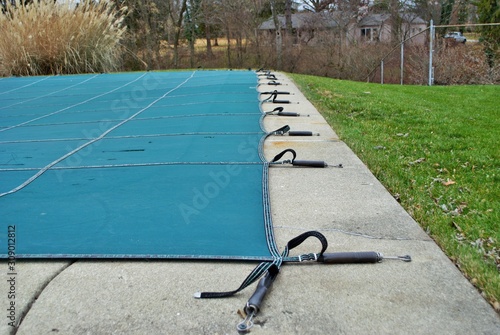 backyard swimming pool with diving board and pool slide tarped up and closed down for winter