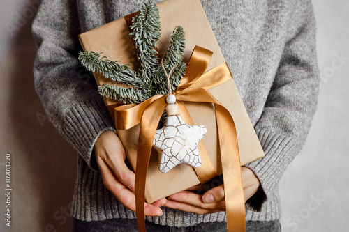 Woman holds a Christmas present in hands. Happy holiday, gift box close-up. Surprise for Boxing day, Christmas and New Year party. Magic time. Celebration winter event. Wrapping paper, toys and ribbon