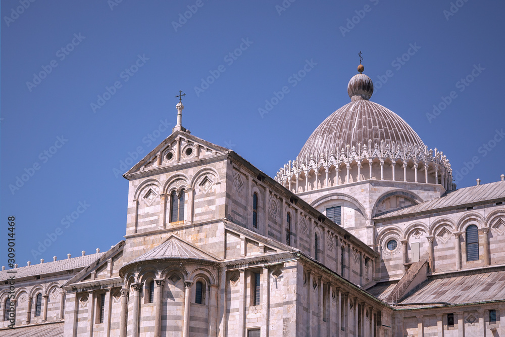 Close up on exterior of Pisa Cathedral. Visible front facade and dome, blue sky. Famous landmark. Tuscany. Italy. No people. 