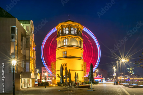 Schlossturm museum in Düsseldorf illuminated at night with ferris wheel in background
