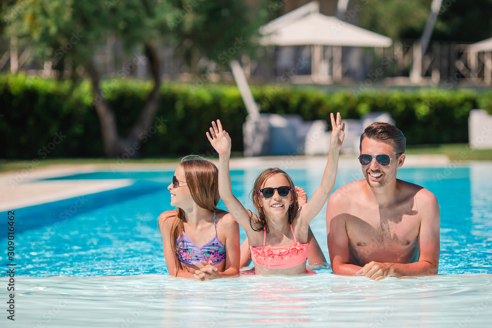 Happy family of three in outdoors swimming pool