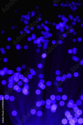 New Year and Christmas color illumination. The illusion of a salute explosion. The quirks of light fiber optic lamp. Blurry circles, bokeh on a dark background. Big explosion.