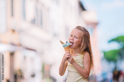 Adorable little girl eating ice-cream outdoors at summer.