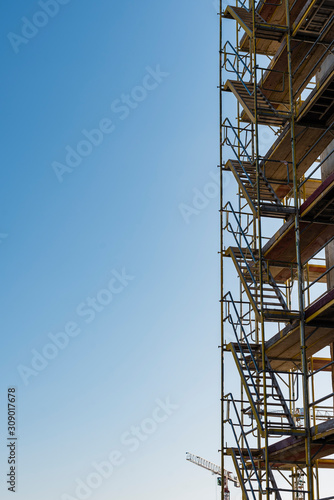 Scaffolding on a construction site, construction site and nice weather, no workers, blue sky, sunny day, scaffolding stairs