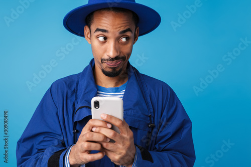 Photo of confused african american man typing on cellphone © Drobot Dean