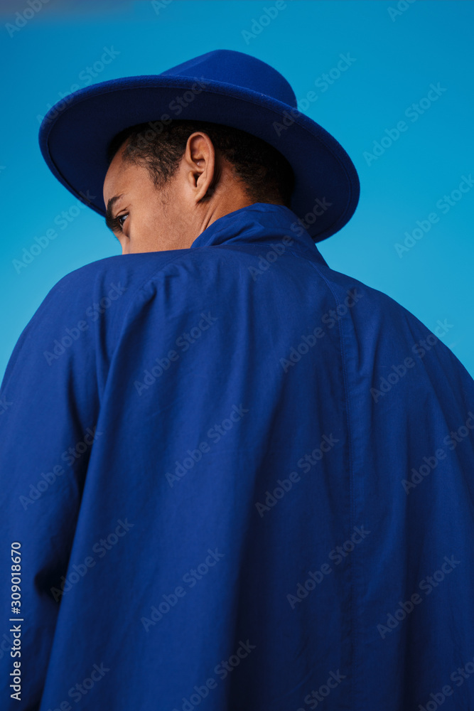 Photo from back of young african american man wearing hat and coat