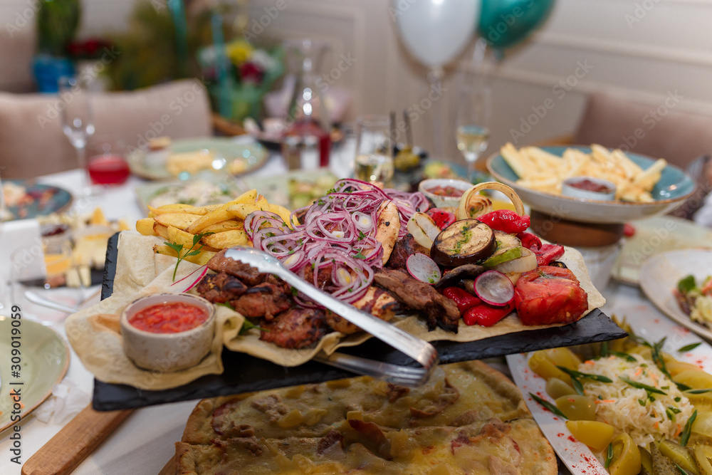 Festive food in restaurant with grilled vegetables, meat, pizza and fried potatoes Festive food in restaurant with grilled vegetables, meat, pizza and fried potatoes