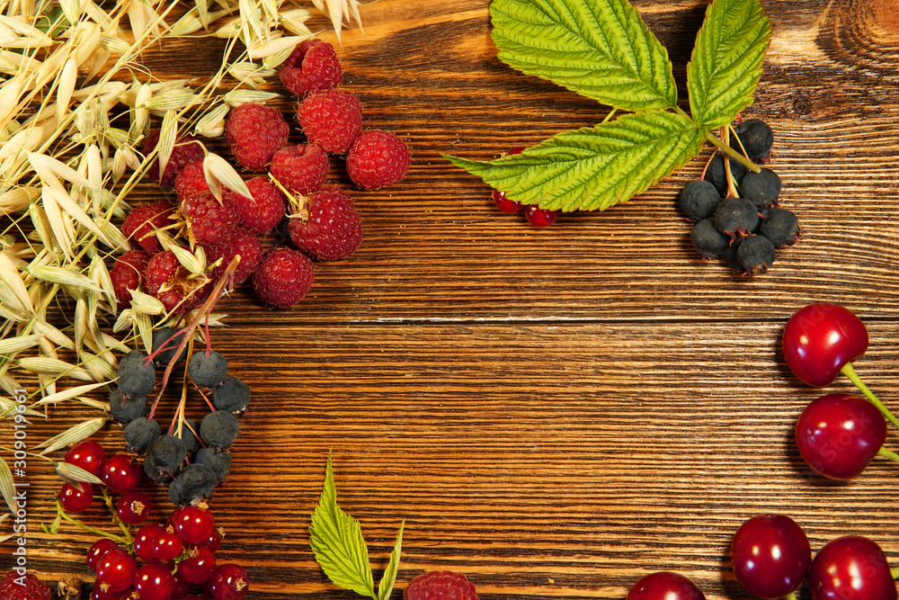 red currant, raspberry, cherry, leaves, cereals on a wooden background.room for text.
