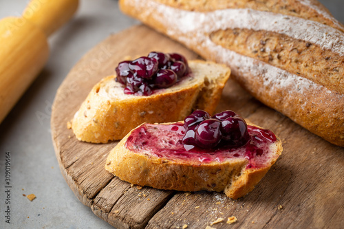 Fresh Homemade Sliced French Baguette Bread with blueberry jam On Wooden Bread Board