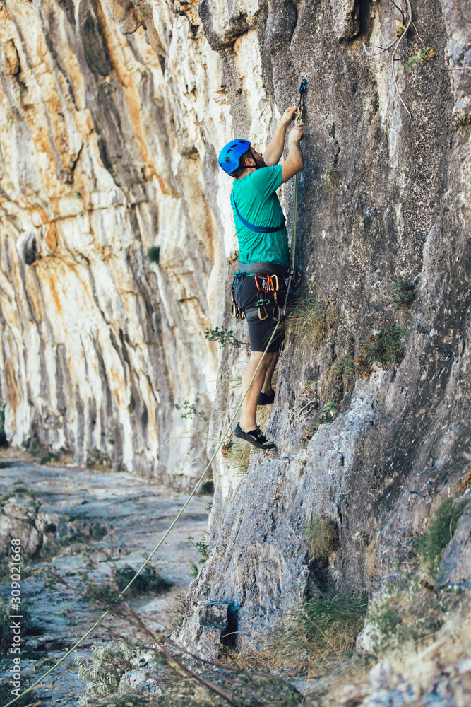 Man with a rope engaged in the sports of rock climbing on the rock.
