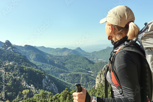 the strong woman with the backpack looks at the green mountains in Turkey