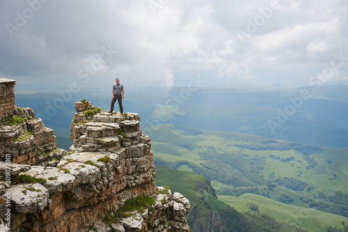 a man stands on the edge of a high cliff