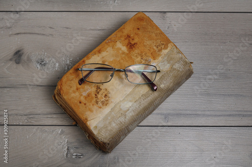 Optical glasses and old book on grey woodboard (ID: 309025874)