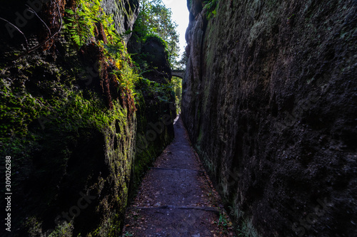 Rocks covered with moss and narrow passage through them.
