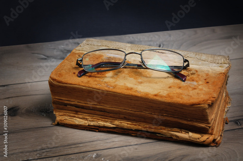 Optical glasses and old book on grey woodboard (ID: 309026807)