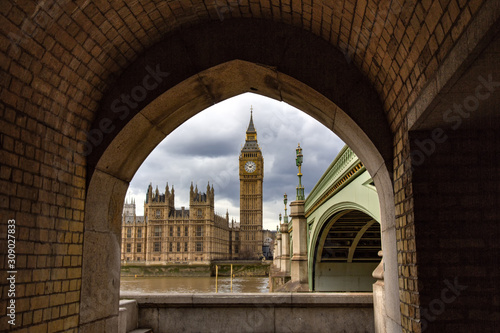 Big Ben (officially known as the Great Bell in the Elizabeth Tower), viewed across the River Thames and framed by a bricked arch.