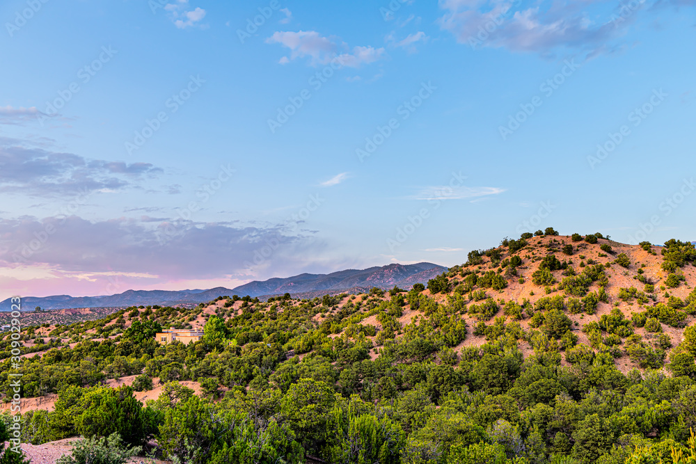 Fototapeta premium Zachód słońca o różowym zmierzchu w Santa Fe w Nowym Meksyku Dzielnica społeczności Tesuque z domami zielone rośliny pignon drzewa krzewy i błękitne niebo chmury