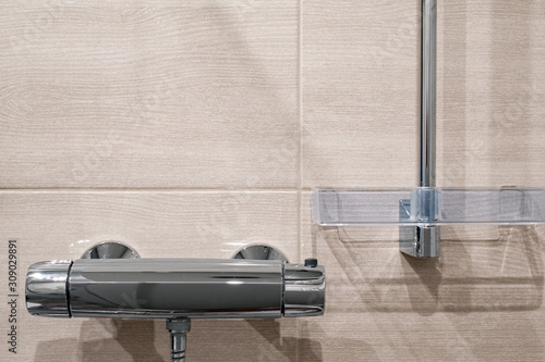 Thermostatic shower faucet on the beige wall in bathroom.