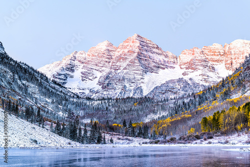 Maroon Bells morning sunrise with sunlight on peak in Aspen, Colorado rocky mountain and autumn yellow foliage view closeup and winter snow frozen lake