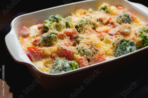 Fresh vegetables in a white ceramic bowl with grated cheese, close up