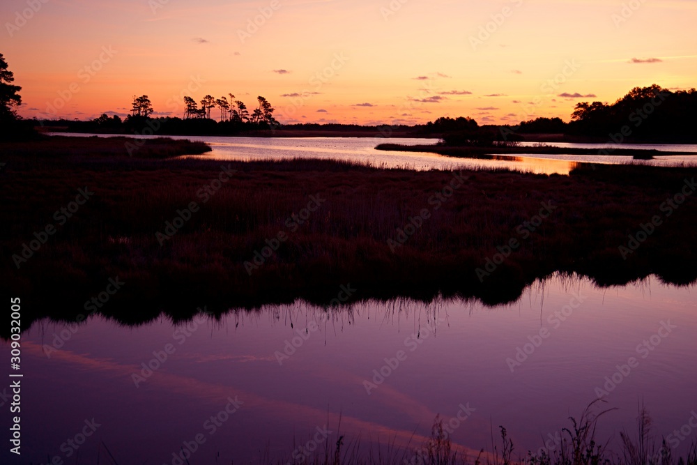 Sunset over Assateague Island over marshes, salt water bay with silhouette
