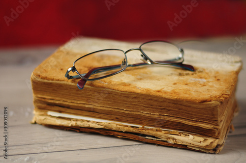 Optical glasses and old book on grey woodboard (ID: 309032096)