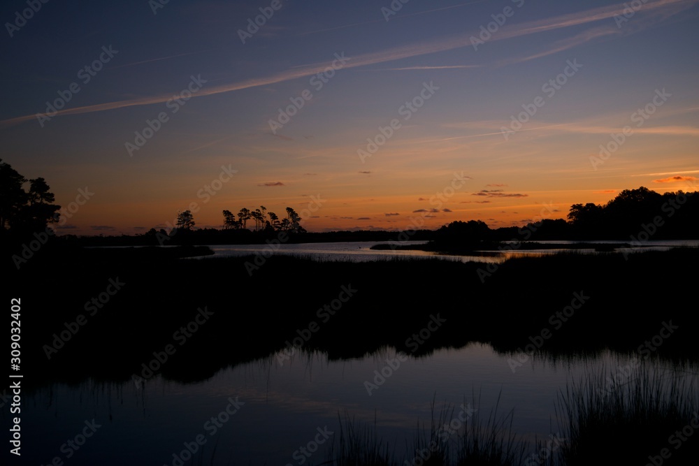 Sunset over Assateague Island over marshes, salt water bay with silhouette Sunset over Assateague Island over marshes, salt water bay with silhouette