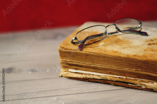 Optical glasses and old book on grey woodboard (ID: 309032493)