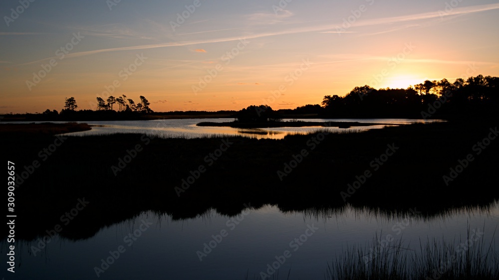 Sunset over Assateague Island over marshes, salt water bay with silhouette