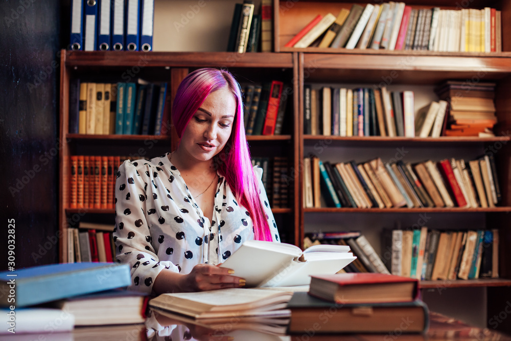 girl reading a book in the library is preparing for exams girl reading a book in the library is preparing for exams